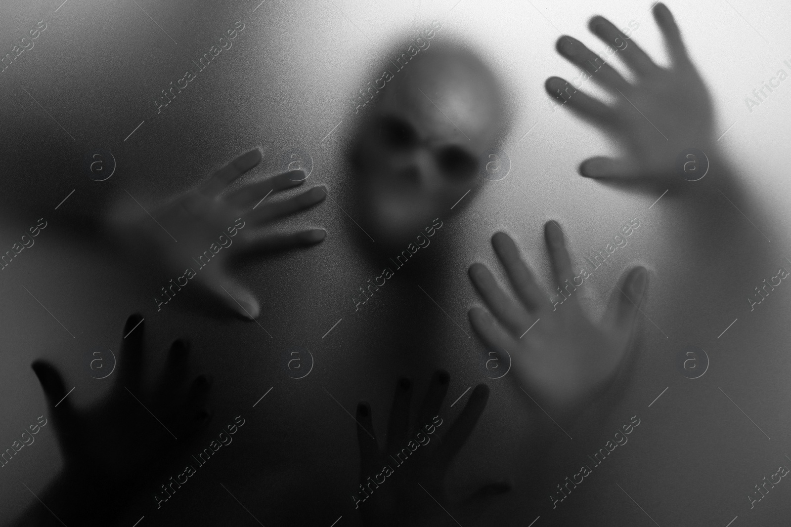 Photo of Silhouette of creepy ghost with skull behind cloth. Black and white effect