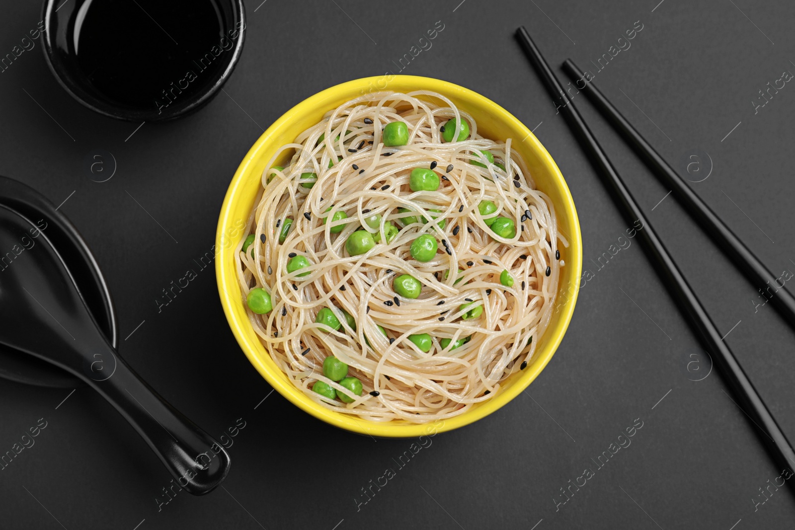 Photo of Bowl of cooked noodles served on black table, flat lay