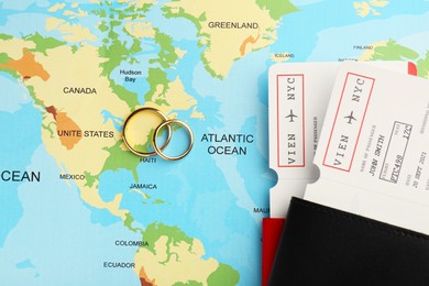 Photo of Honeymoon concept. Plane tickets, passports and golden rings on world map, top view