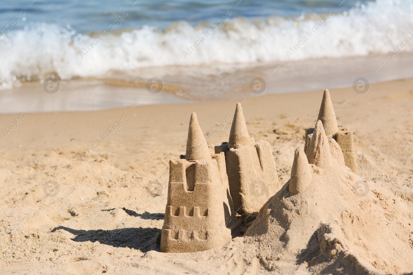 Photo of Beach with sand castle near sea on sunny day