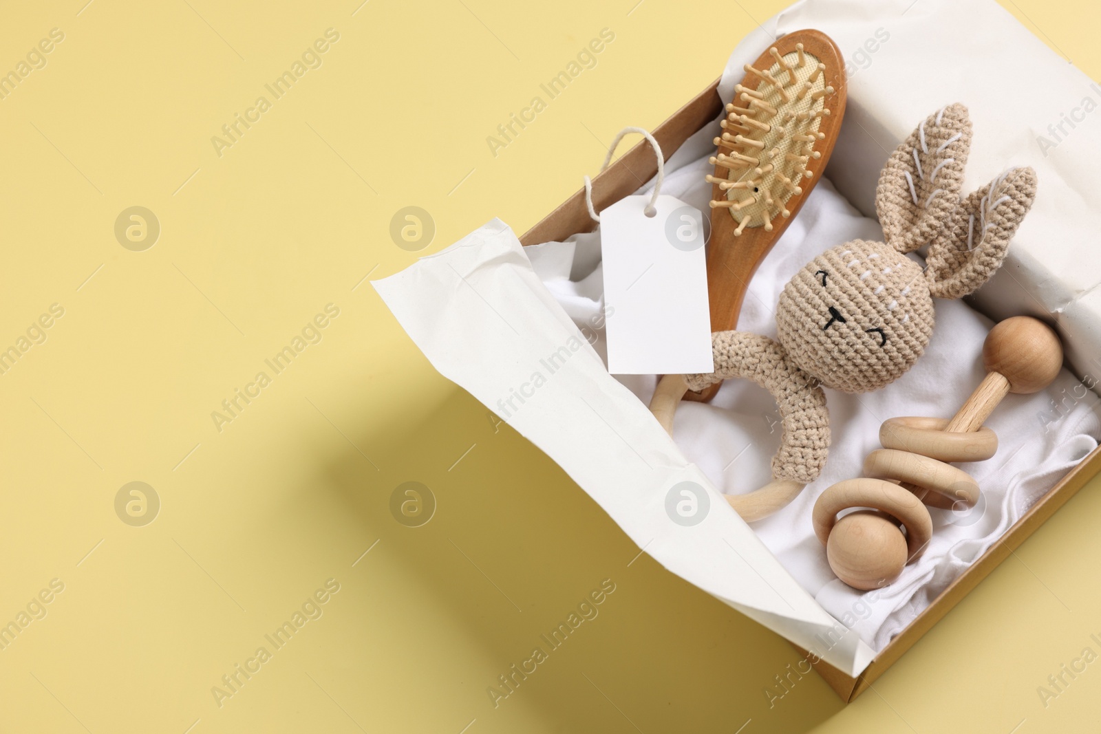 Photo of Different baby accessories and blank card in box on yellow background, top view. Space for text