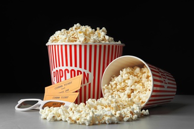 Photo of Popcorn, cinema tickets and 3d glasses on grey table