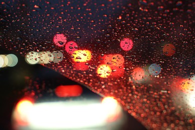 Blurred view of road through wet car window at night. Bokeh effect