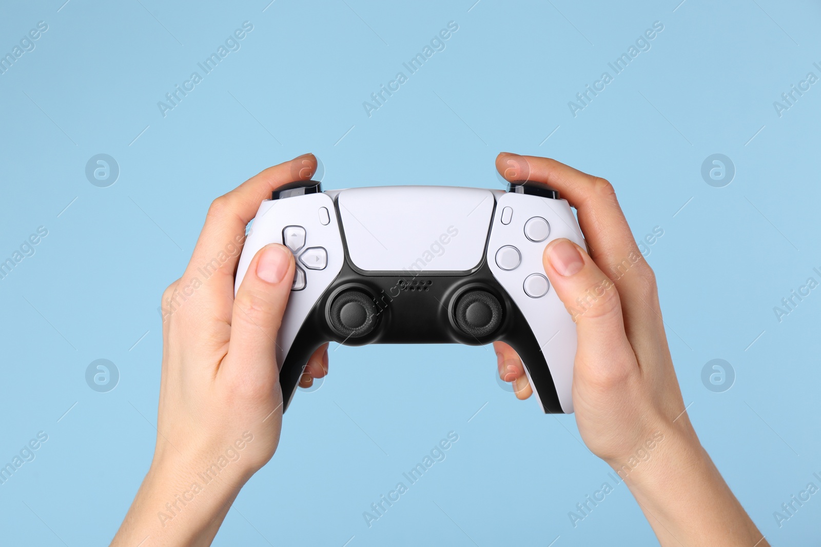 Photo of Woman using game controller on light blue background, closeup