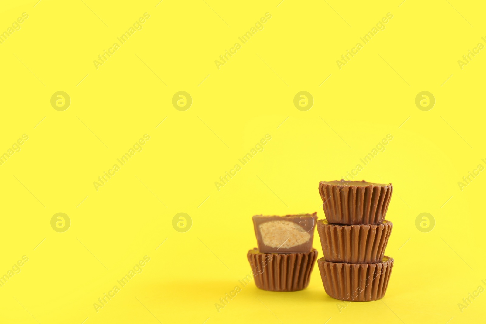 Photo of Sweet peanut butter cups on yellow background. Space for text