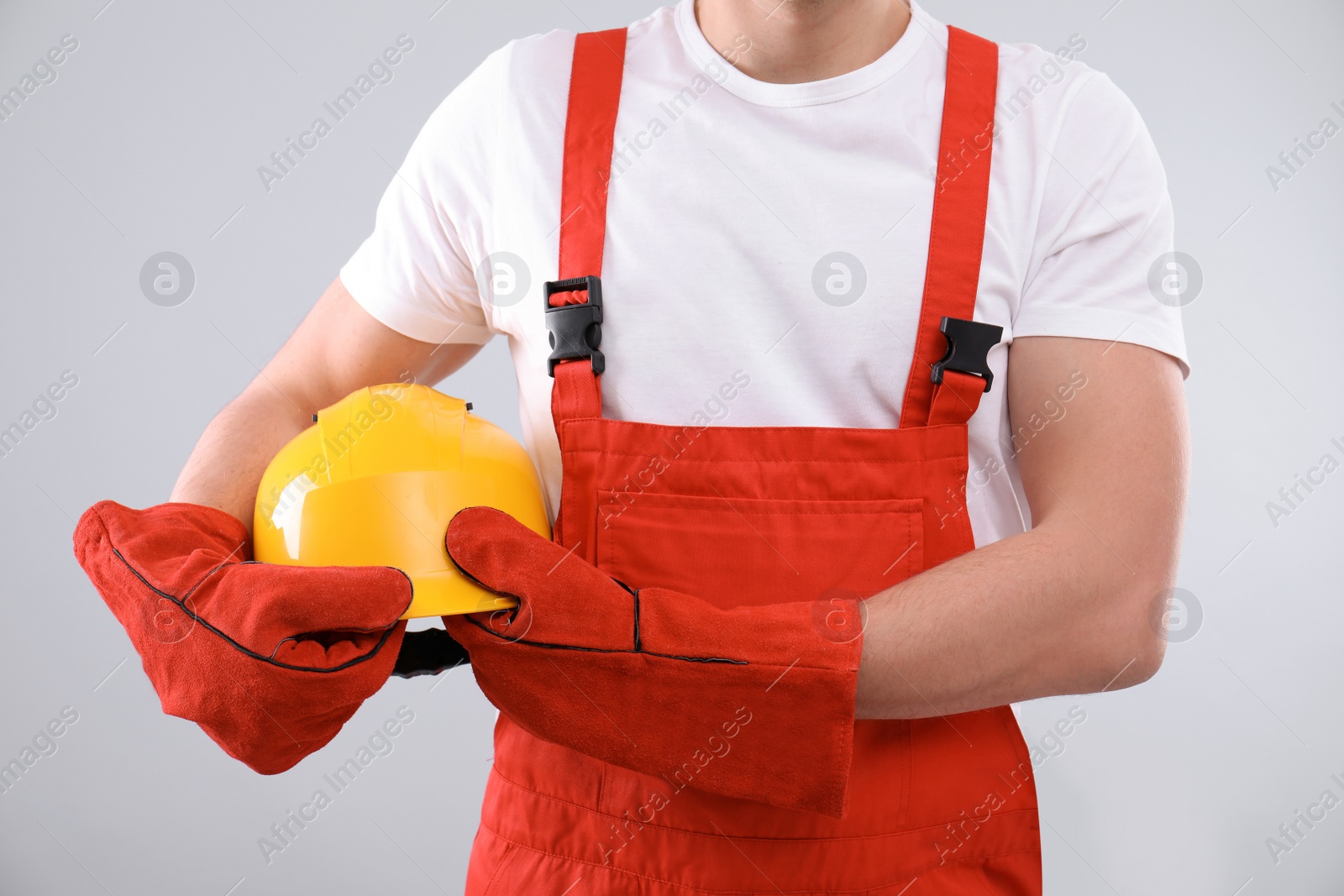 Photo of Male industrial worker in uniform on light background, closeup. Safety equipment