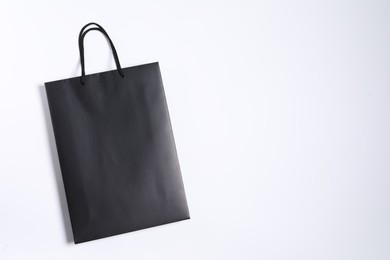 Photo of One black paper shopping bag on white background, top view. Space for text