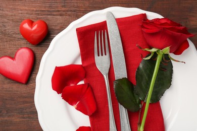 Photo of Romantic place setting with red rose and decorative hearts on wooden table, top view. St. Valentine's day dinner