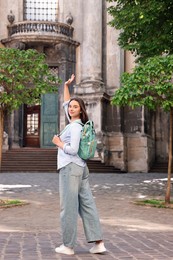 Photo of Travel blogger with backpack recording video on city street