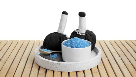 Bowl with blue sea salt and herbal bags on wooden table against white background