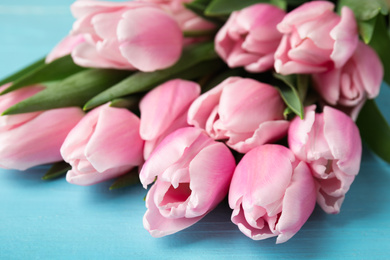 Photo of Beautiful pink spring tulips on light blue background, closeup