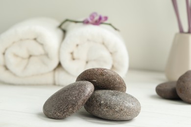 Photo of Pile of spa stones on white wooden table, closeup