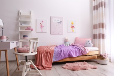 Comfortable bed with pink linens in children's room