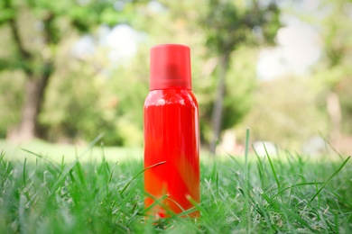 Bottle of insect repellent spray on grass