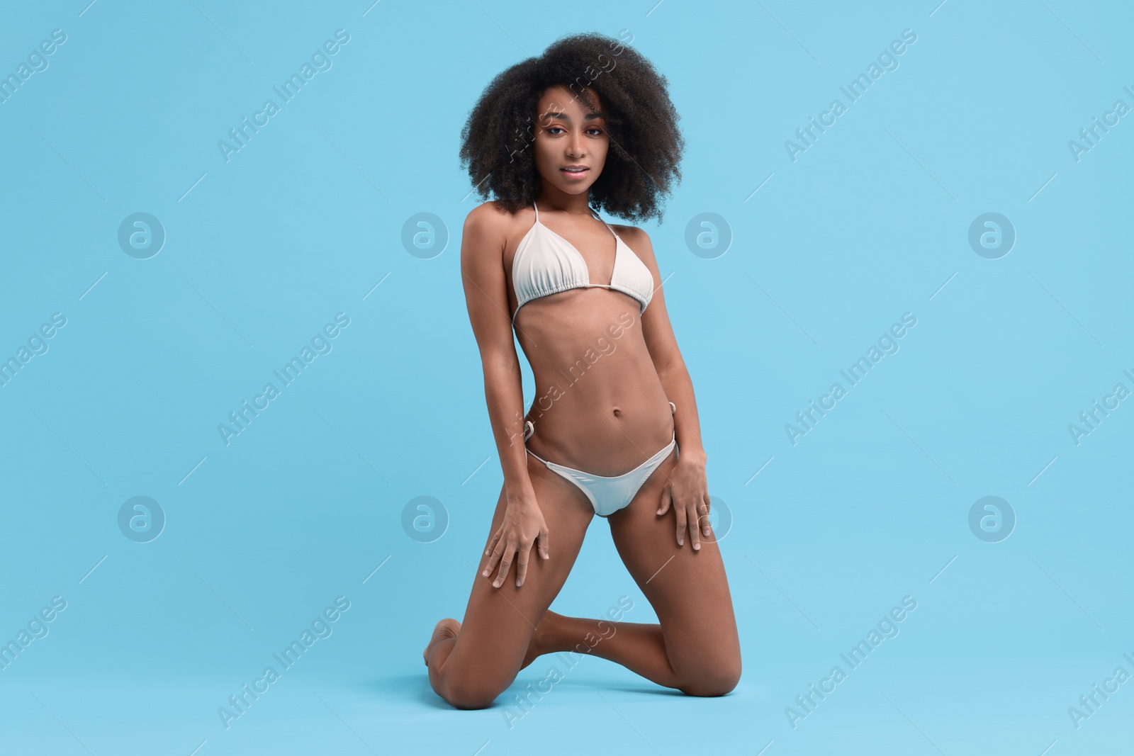 Photo of Beautiful woman in stylish bikini posing on light blue background