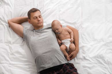 Photo of Father and baby sleeping on bed together, top view