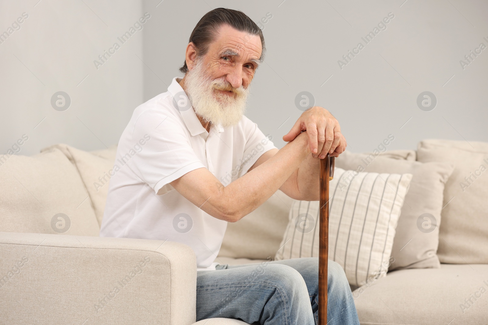 Photo of Senior man with walking cane on sofa indoors