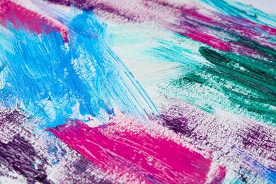 Photo of Strokes of colorful acrylic paints on white canvas, closeup