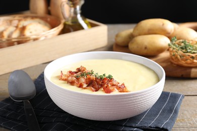 Photo of Tasty potato soup with bacon and rosemary in bowl served on wooden table