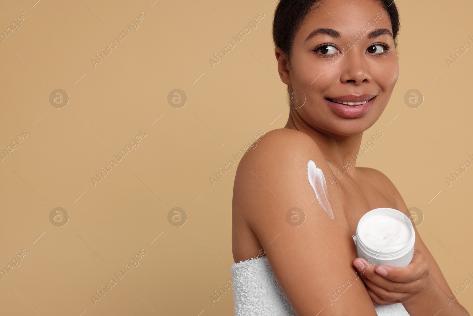 Photo of Young woman with body cream on beige background. Space for text