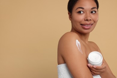 Photo of Young woman with body cream on beige background. Space for text