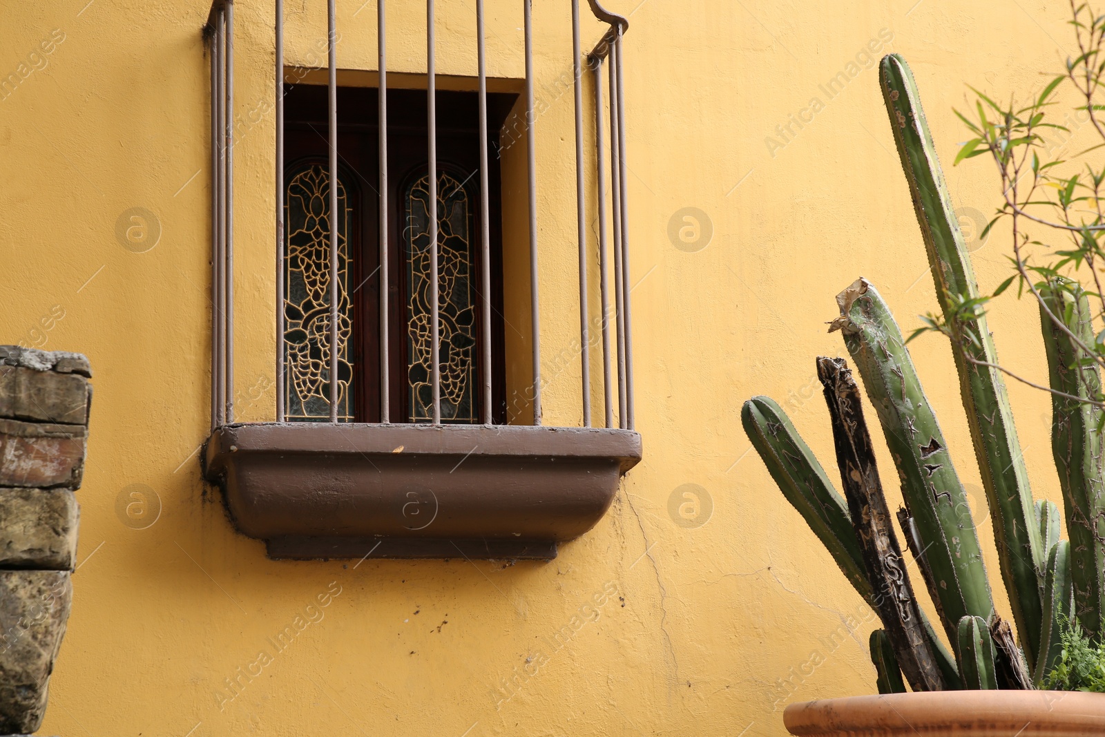 Photo of Yellow building with beautiful window and steel grilles