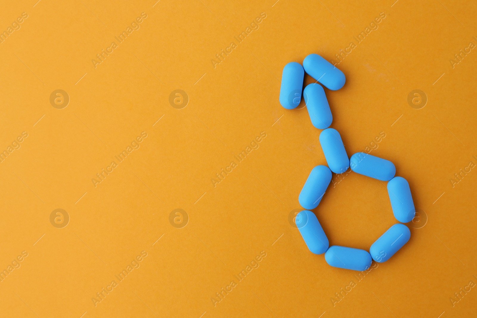 Photo of Pills and space for text on orange background, top view. Potency problem