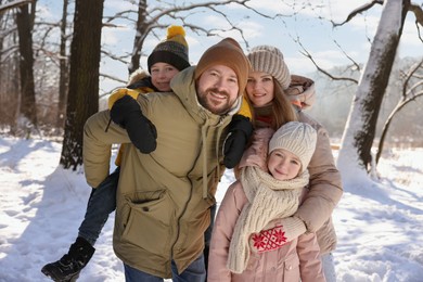 Portrait of happy family in sunny snowy forest