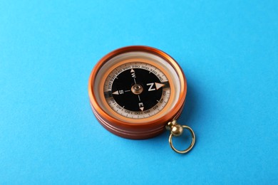 Photo of One compass on light blue background. Tourist equipment