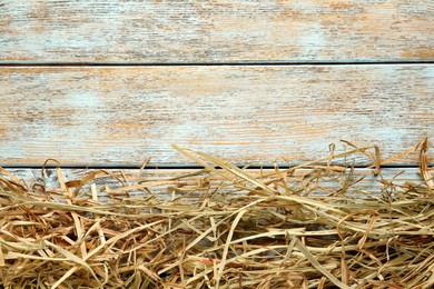 Heap of dried hay on light wooden background, flat lay. Space for text