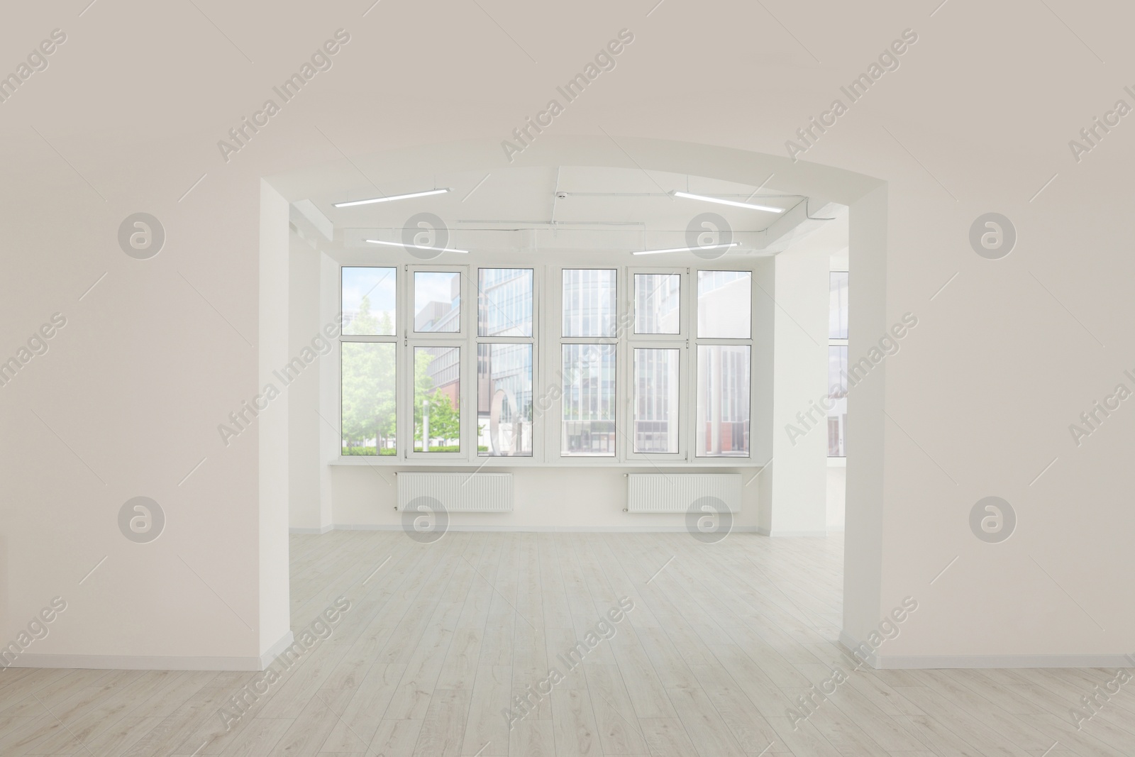 Photo of Empty office room with white walls, clean windows and modern lights on ceiling. Interior design