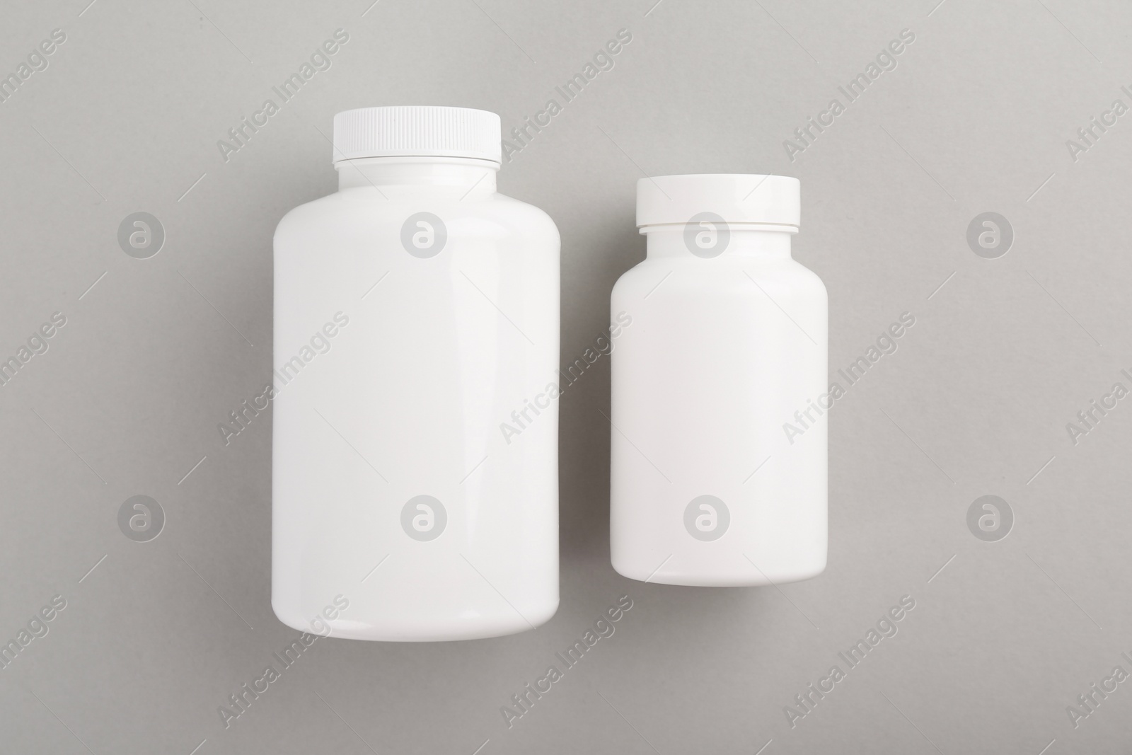 Photo of Blank white pill bottles on light grey background, top view