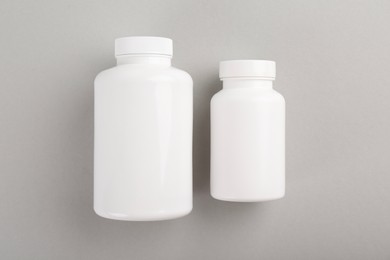 Blank white pill bottles on light grey background, top view