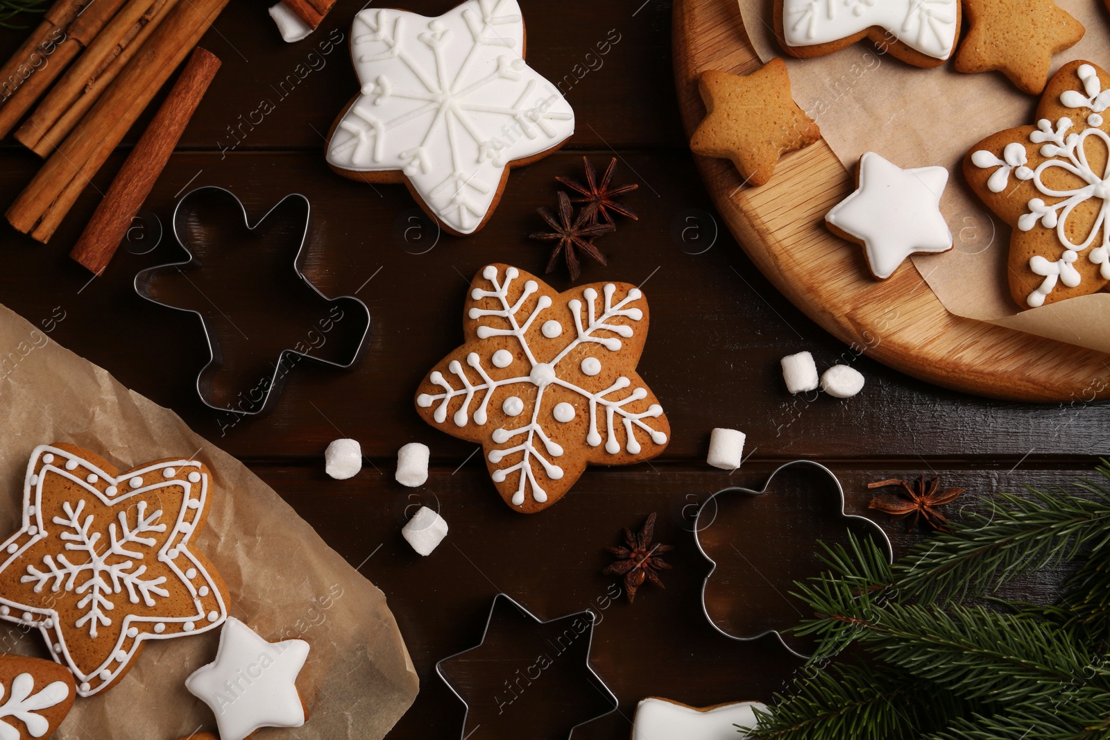 Photo of Decorated Christmas cookies and fir tree branches on wooden table, flat lay