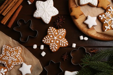 Decorated Christmas cookies and fir tree branches on wooden table, flat lay