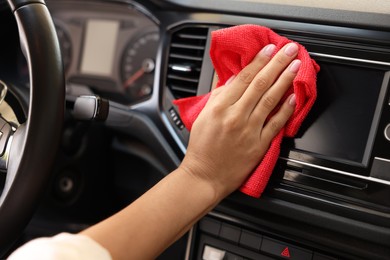 Photo of Woman cleaning center console with rag in car, closeup