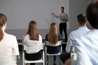 Photo of Male business trainer with laptop giving lecture in conference room with projection screen