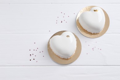 Photo of St. Valentine's Day. Delicious heart shaped cakes and confetti on white wooden table, flat lay. Space for text