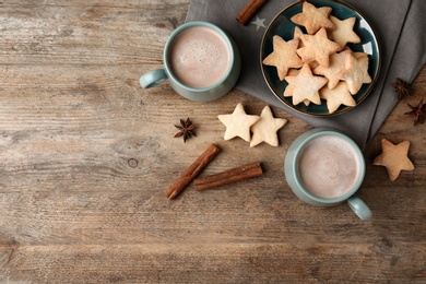 Composition with delicious hot cocoa drink and cookies on wooden background, flat lay