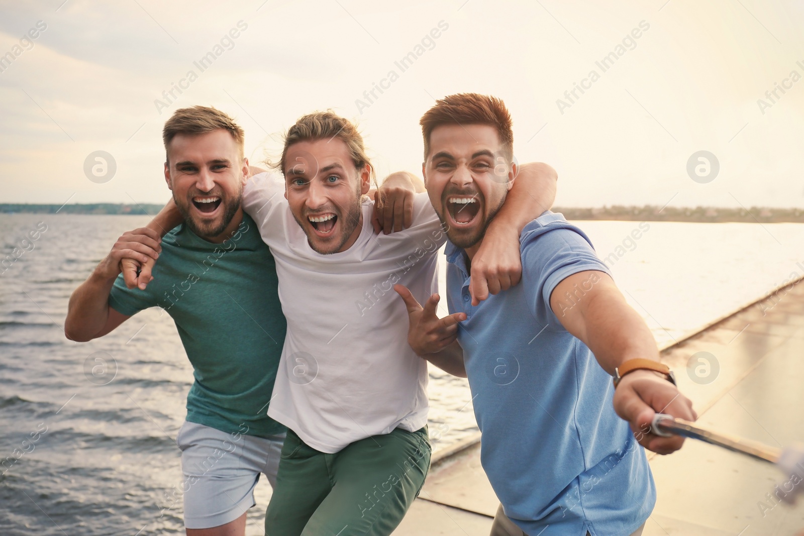 Photo of Happy young men taking selfie outdoors on sunny day