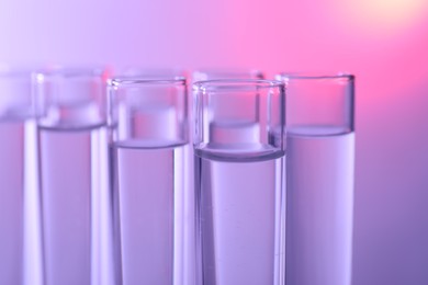 Many glass test tubes on color background, closeup