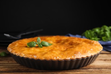 Delicious pie with meat and basil on wooden table