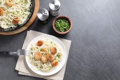 Delicious scallop pasta with green onion served on grey table, flat lay. Space for text