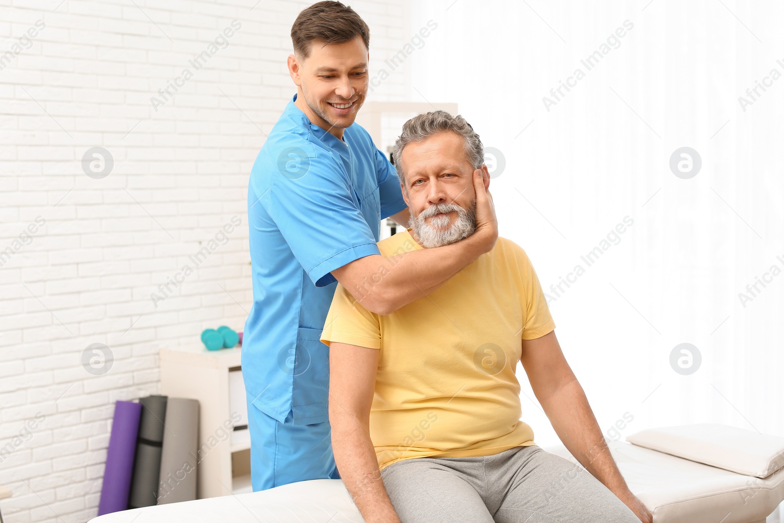 Photo of Physiotherapist working with patient in clinic. Rehabilitation therapy