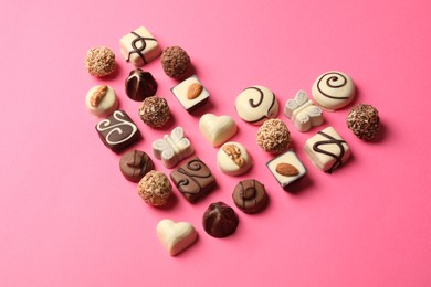 Photo of Heart made with delicious chocolate candies on pink background, top view