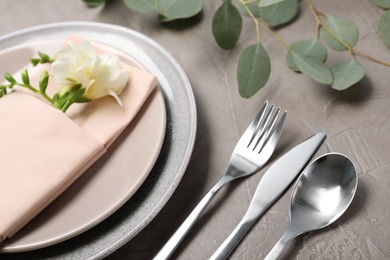 Festive table setting with plates, cutlery and napkin on grey background, closeup