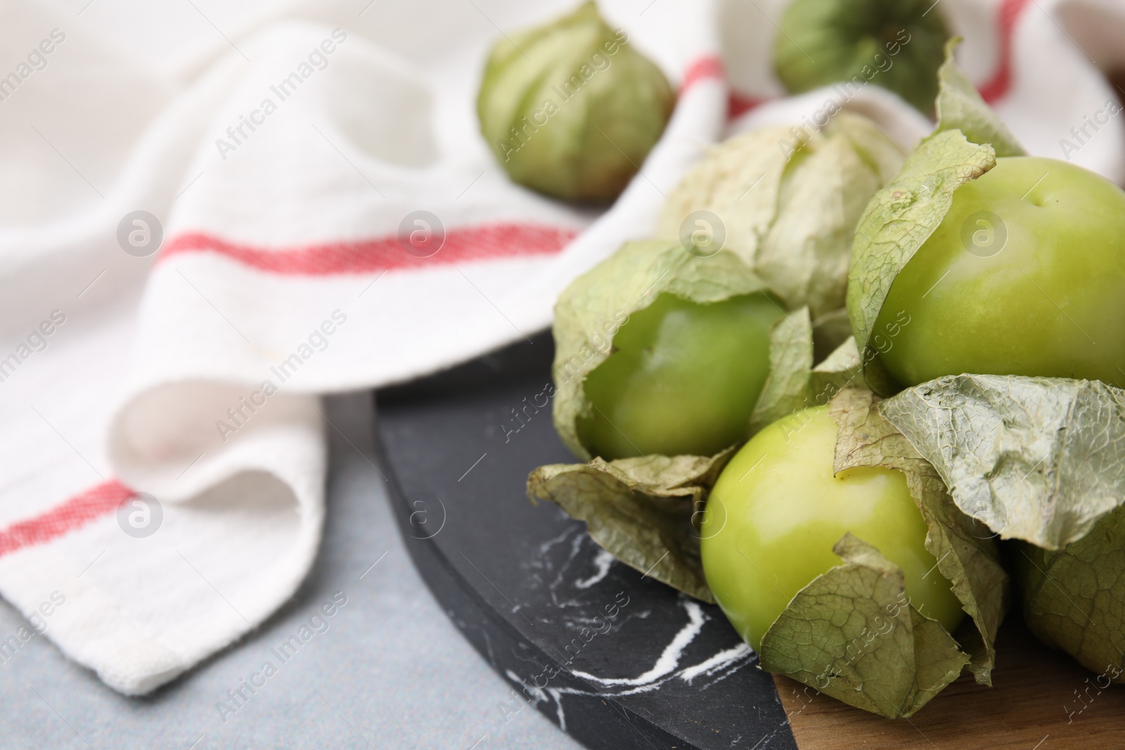 Photo of Fresh green tomatillos with husk on gray table, closeup