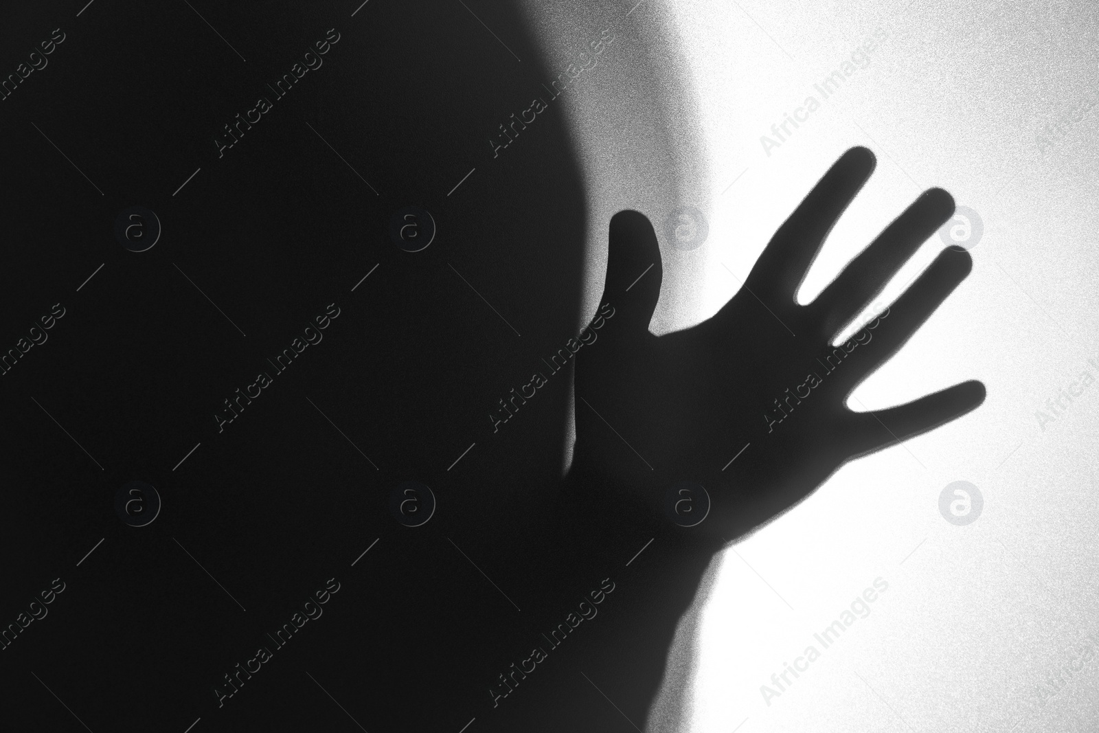 Photo of Silhouette of ghost behind glass against white background, closeup