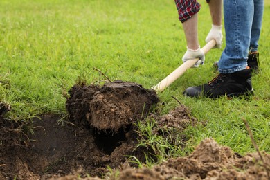 Photo of Worker digging soil with shovel outdoors, closeup