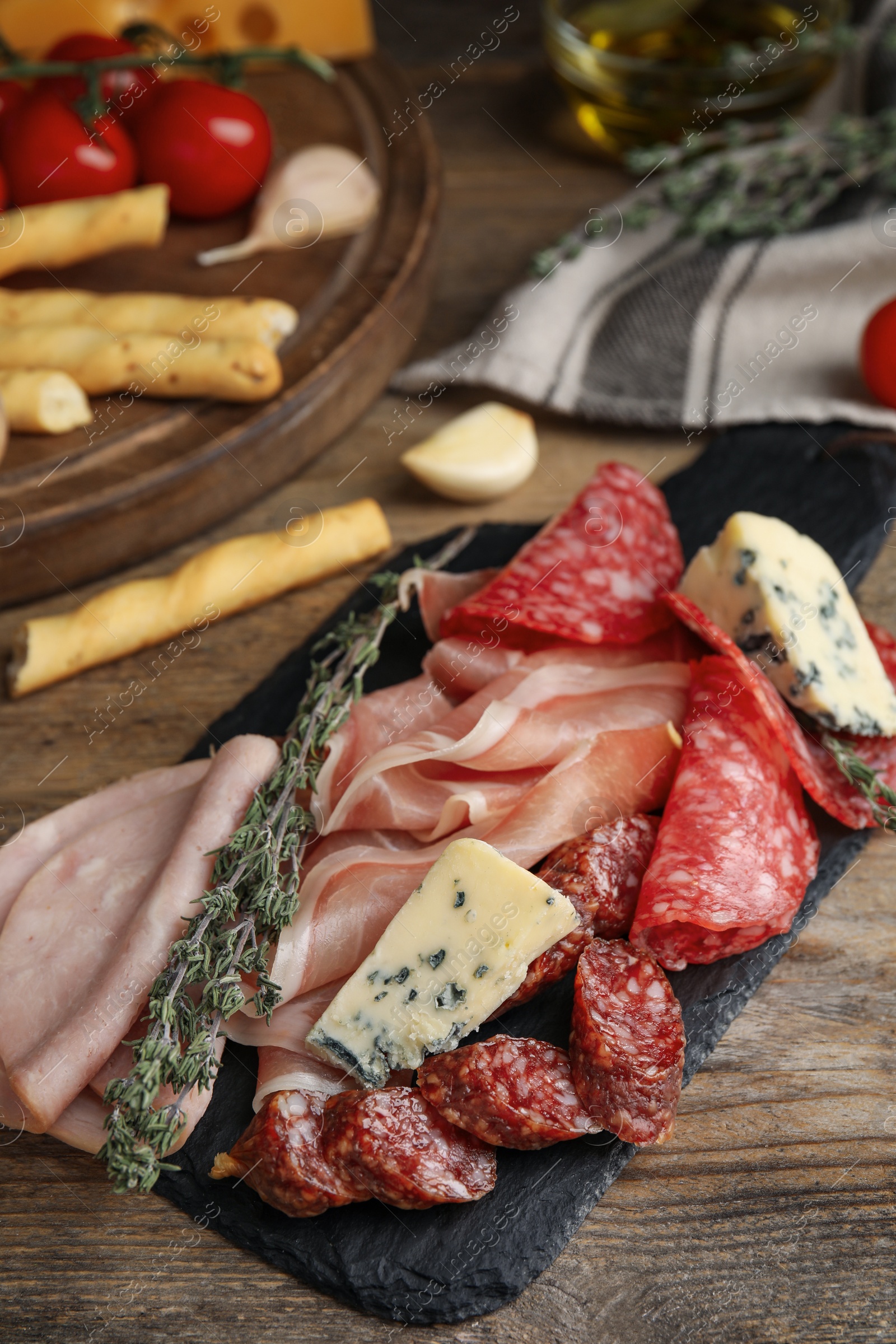 Photo of Tasty ham with other delicacies served on wooden table